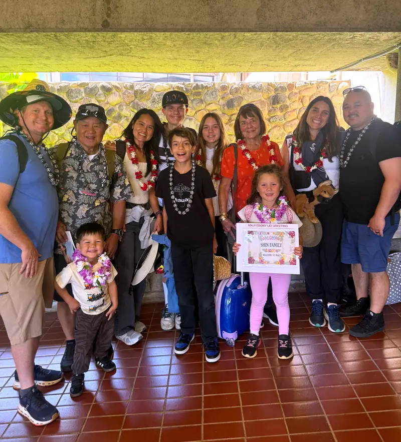Large multigenerational family in lei holding a lei greeting certificate