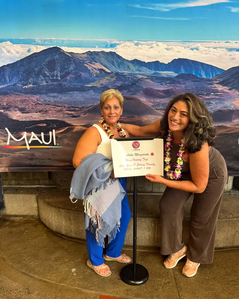 Two travelers in orchid lei holding their lei greeting certificate