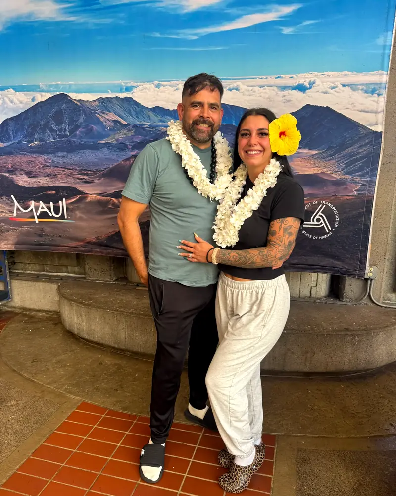 A couple wearing fresh orchid lei, greeted on arrival at Kahului Airport on Maui