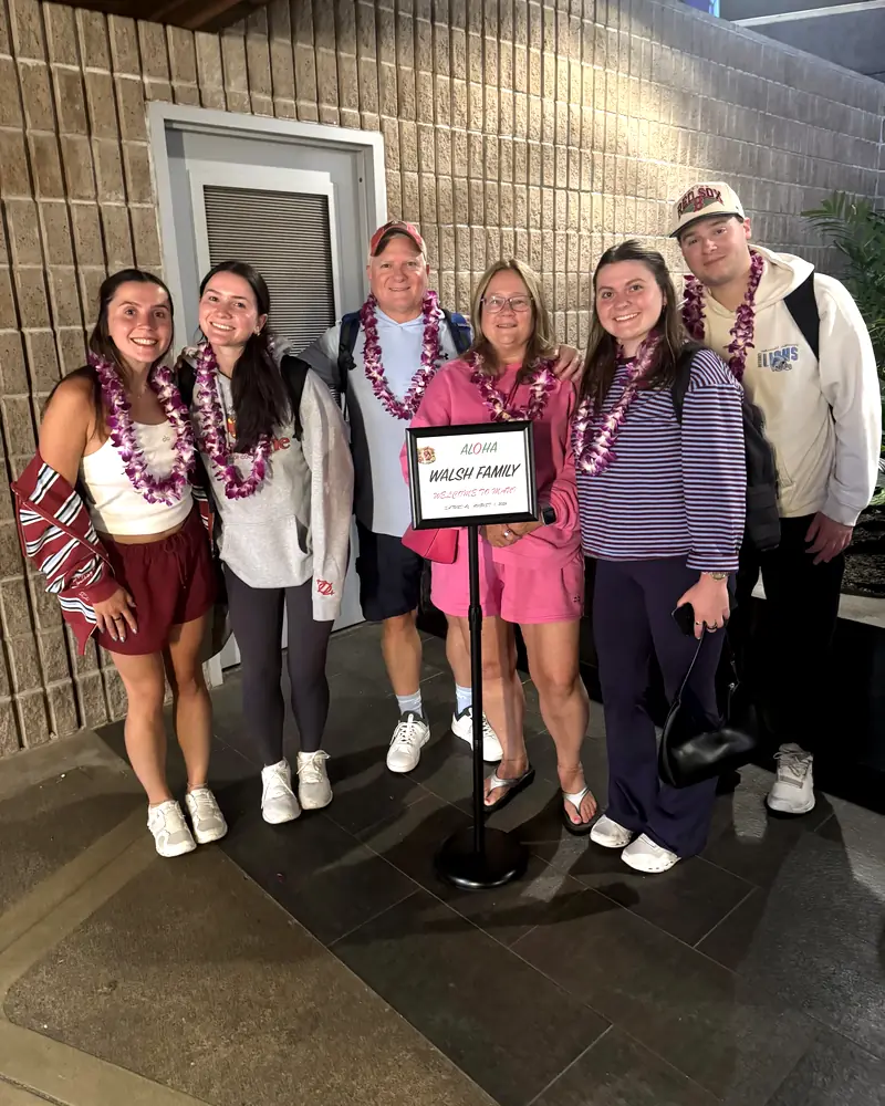Group of friends in orchid lei greeted on an evening arrival