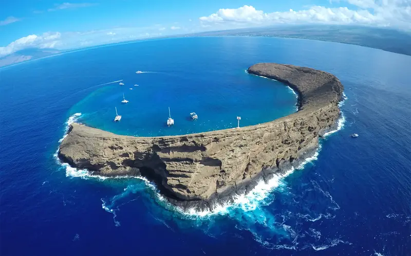 Aerial view of the crescent-shaped Molokini crater with boats moored inside