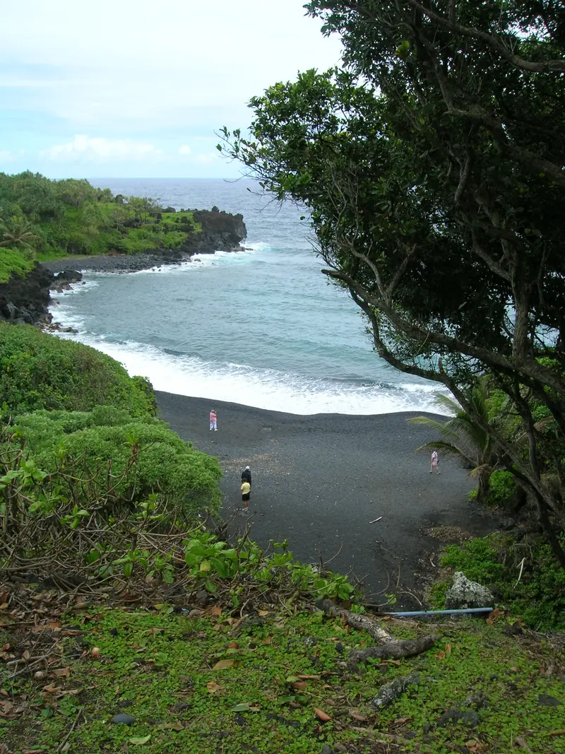 The black sand beach at Waiʻānapanapa State Park, framed by green vegetation
